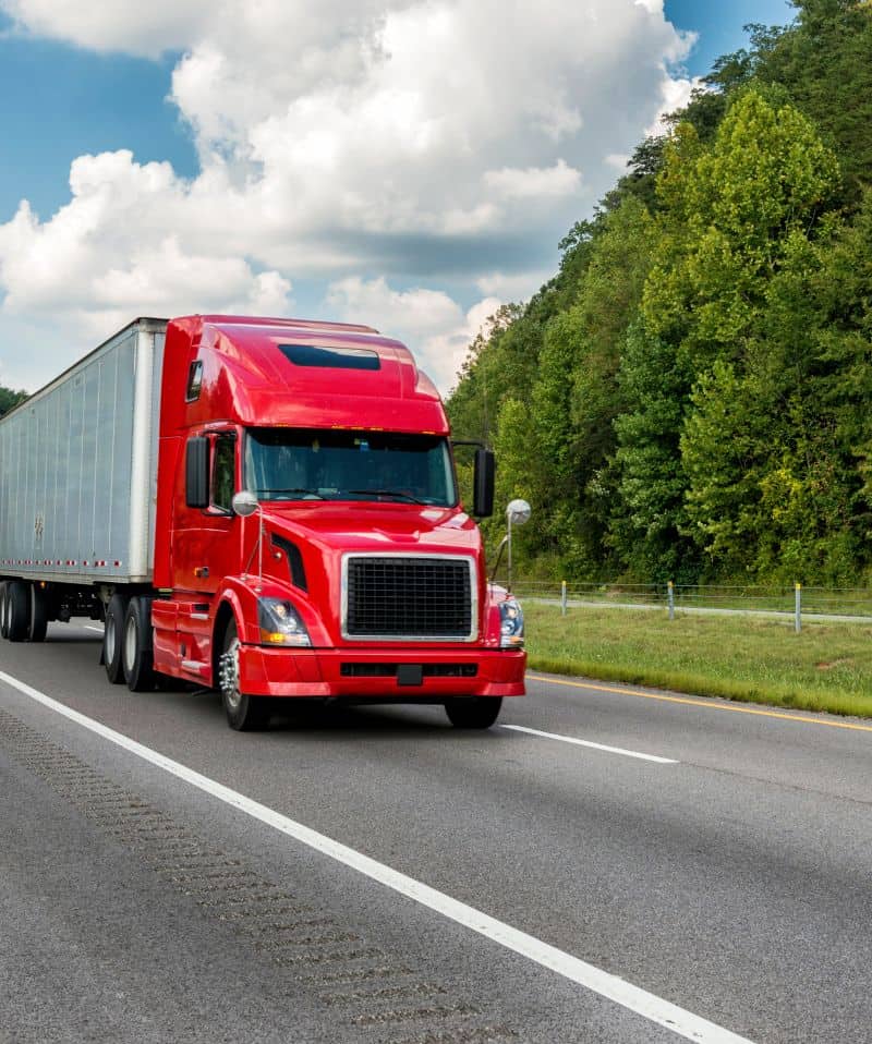 red semi truck and trailer driving down road DOT