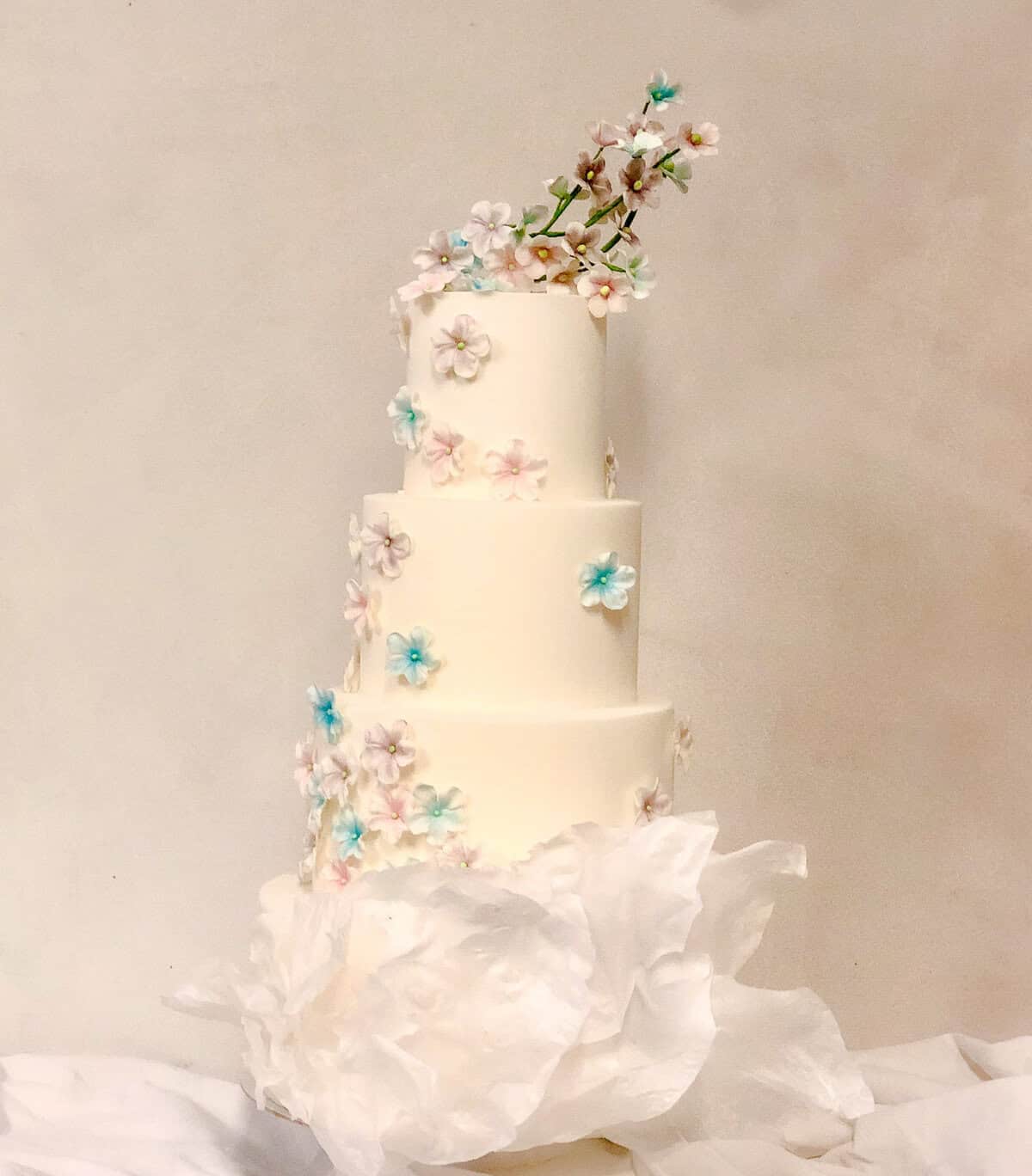 White tiered wedding cake with pastel sugar flowers at Castello di Celsa in Tuscany, Italy.