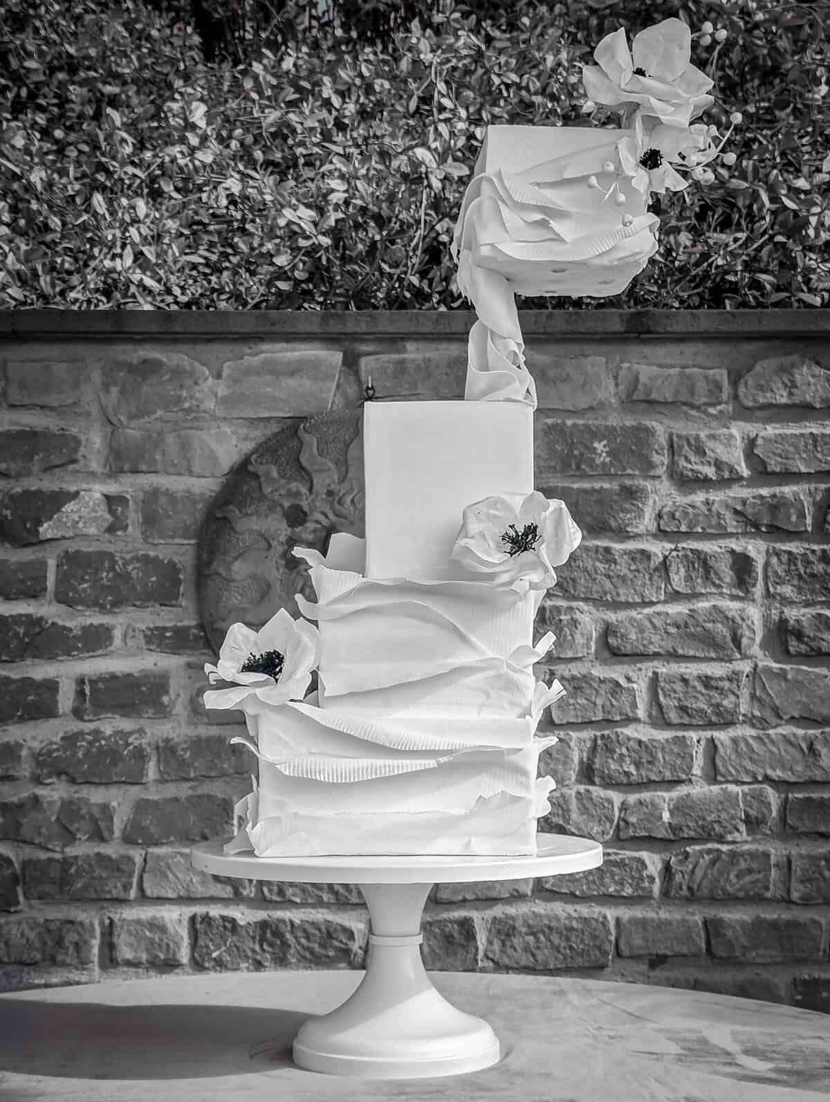 Modern white sculptural wedding cake with dramatic ruffled tiers and white sugar flowers at Collegio alla Querce in Florence, Italy.