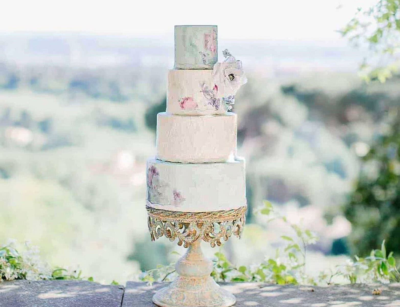 White tiered wedding cake with watercolor blue and pink painted effect at a villa near Florence, Tuscany, Italy.