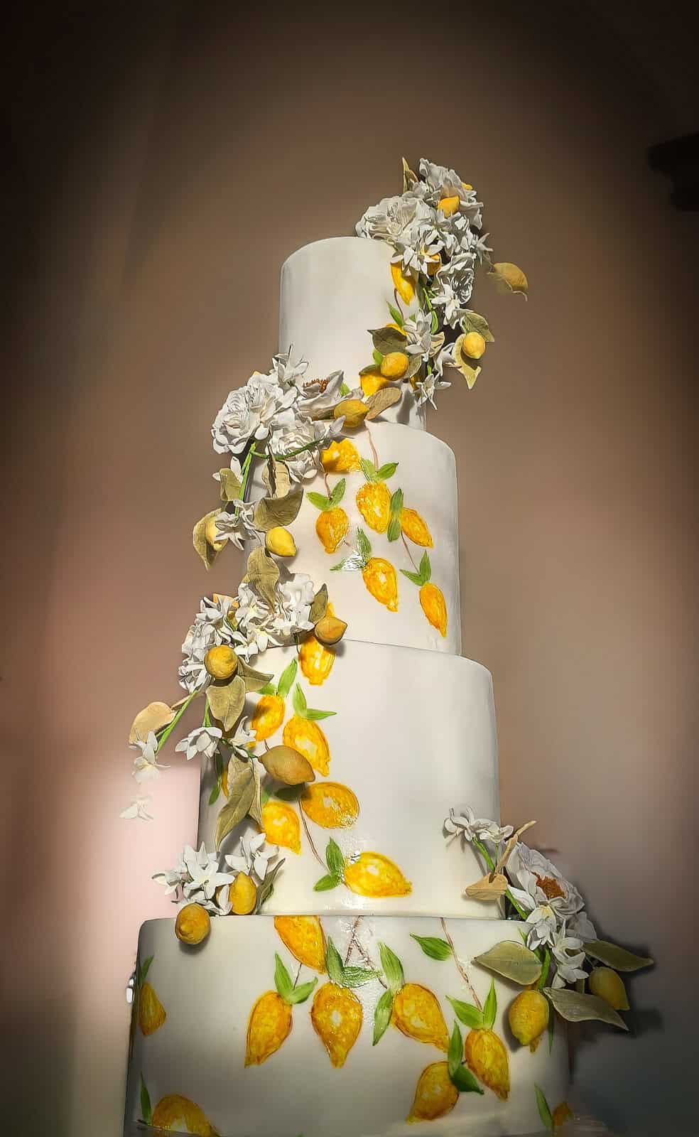 Hand-painted lemon tiered wedding cake with cascading sugar flowers at a destination wedding in Tuscany, Italy.