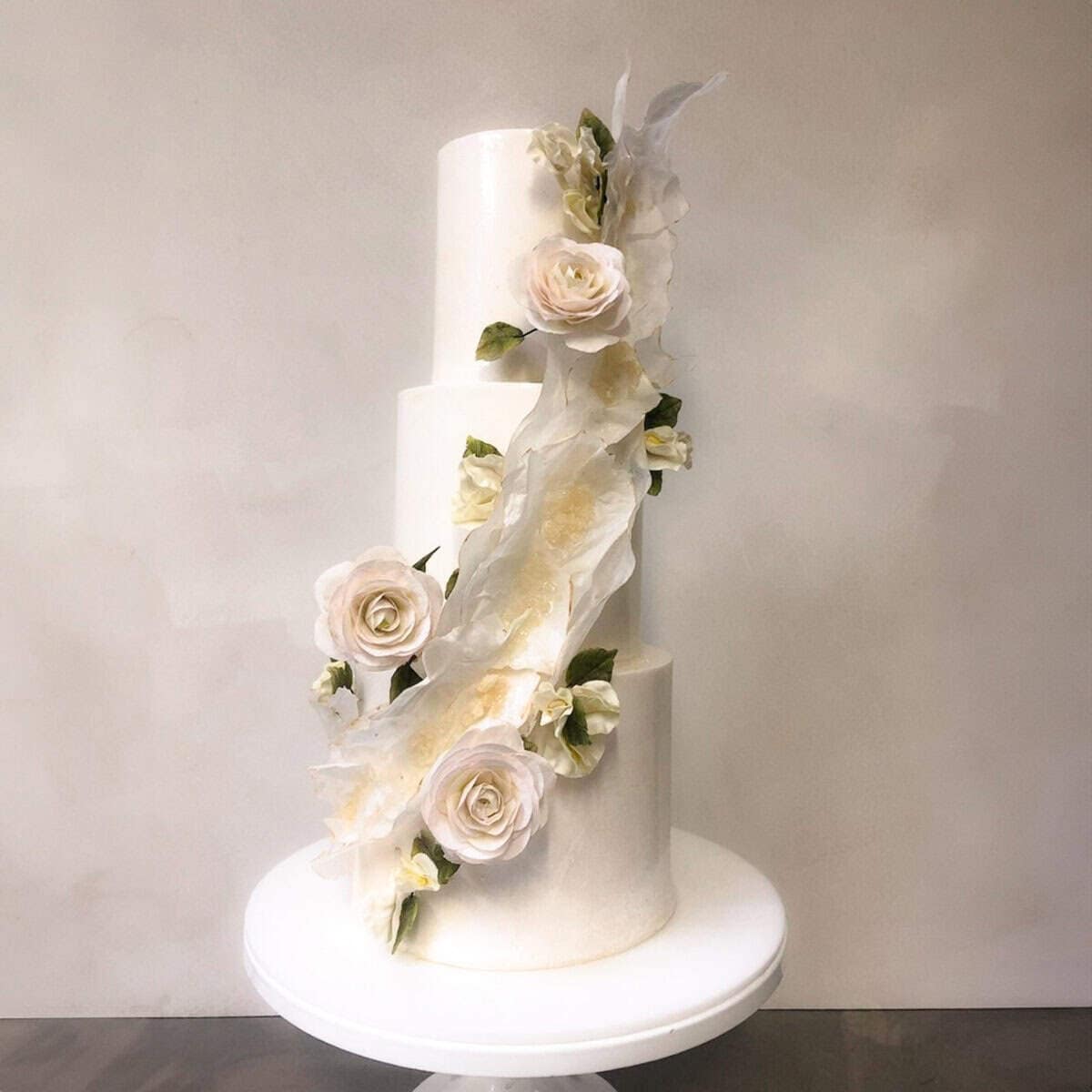 White tiered wedding cake with sculptural ruffle detail and handcrafted sugar roses at a villa in Tuscany, Italy.
