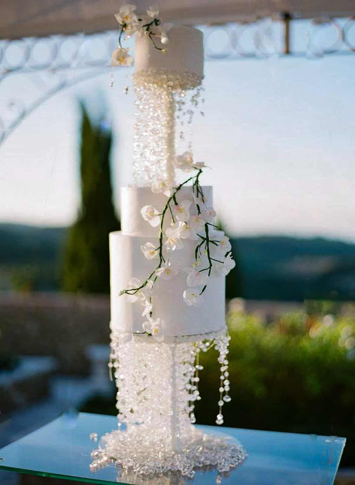 Luxury wedding cake with cascading Swarovski crystals and white sugar orchids at a villa in Tuscany, Italy.