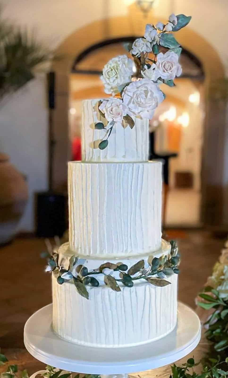White tiered wedding cake with handcrafted sugar olive branches and flowers at a destination wedding in Tuscany, Italy.
