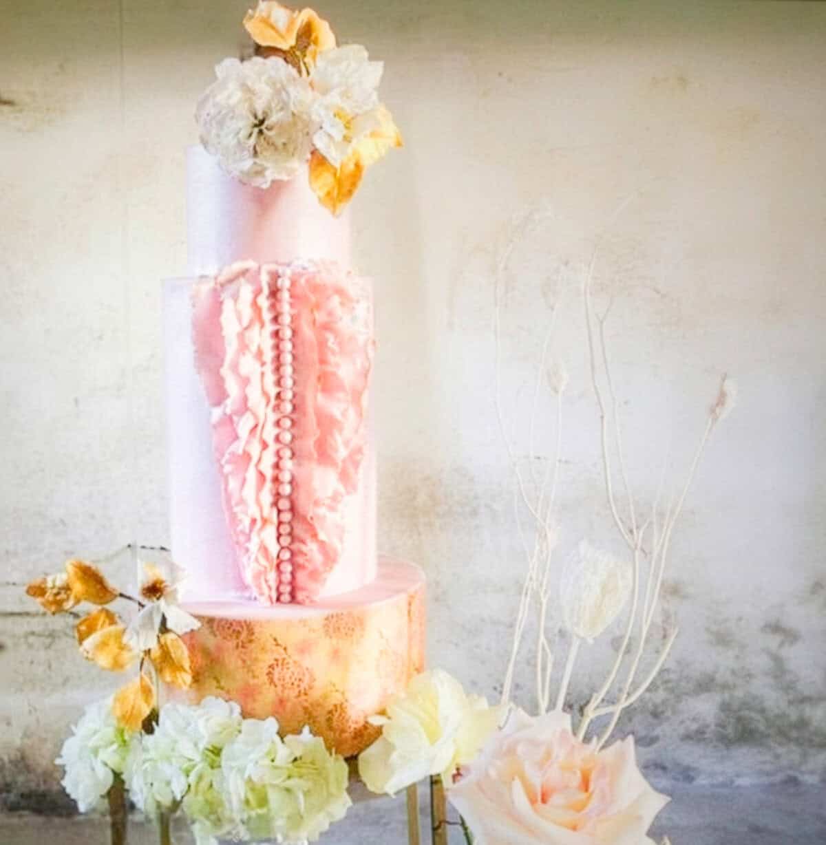 Luxury couture-inspired wedding cake with sculptural ruffles, pink tiers, and gold pattern at Villa Centinale in Tuscany, Italy.