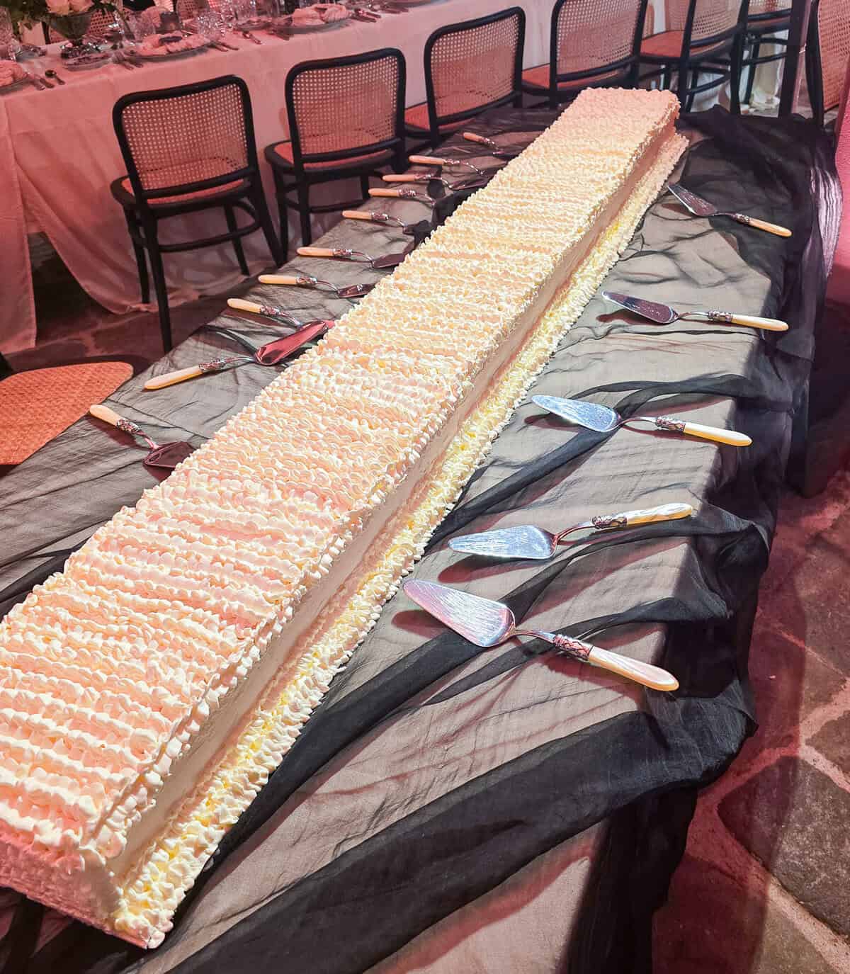 Extra-long wedding cake with piped cream finish on a serving table at Villa Centinale in Tuscany, Italy.