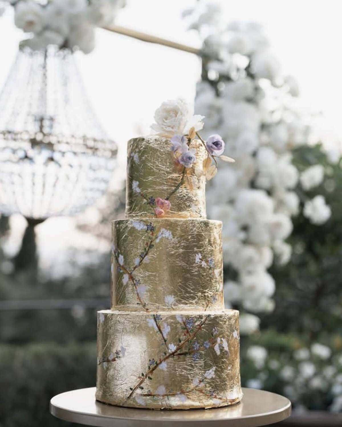 Chinoiserie-inspired gold leaf tiered wedding cake with delicate floral details at Villa San Michele in Fiesole, Italy.