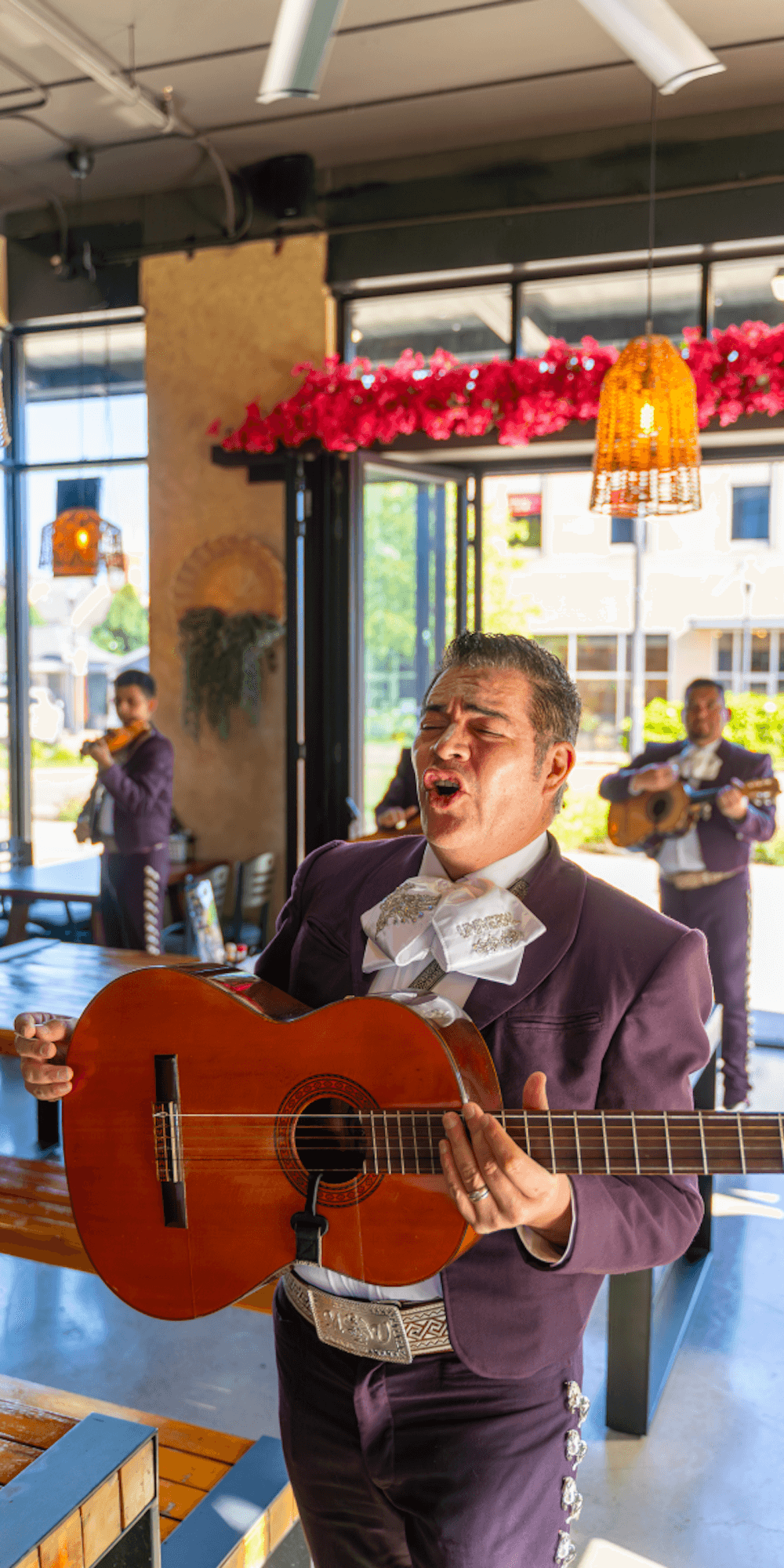 Mariachi musician singing and playing guitar at Vallarta event.