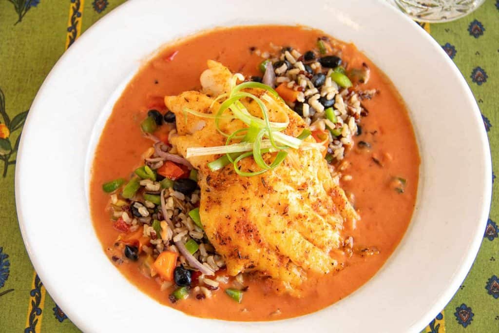 Blackened grouper fillet served with rice and vegetable medley in a creamy sauce.