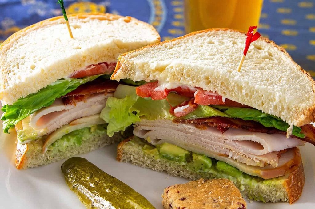 Close-up of a fresh club sandwich with lettuce, tomato, turkey, and bacon.