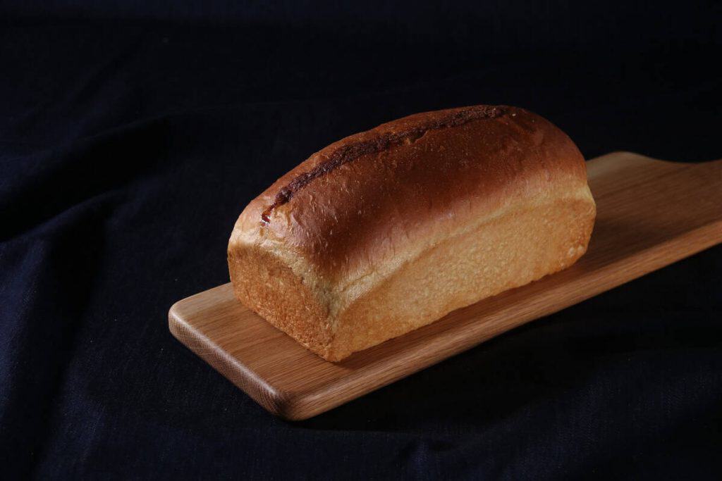 Freshly baked bread loaf on wooden board at Village Baker.
