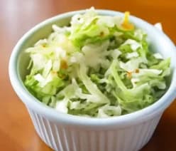 Crispy shredded cabbage and carrots for coleslaw in a white bowl.