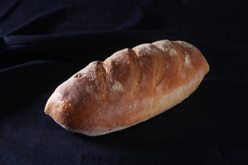 Crusty French bread loaf on black background.