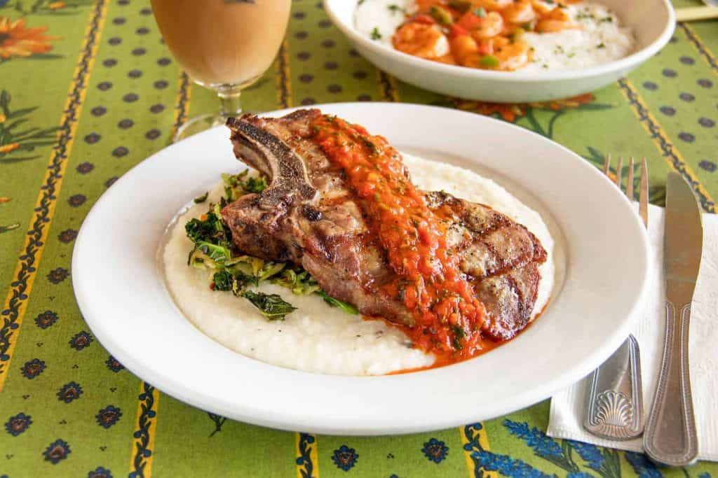 Juicy pork ribeye steak with tomato sauce on a white plate.