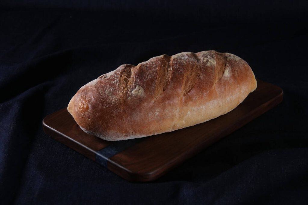 Crusty sourdough bread loaf on wooden board for bakery.