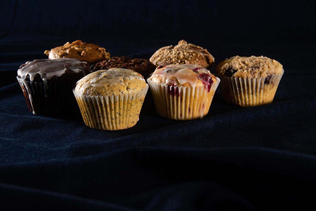 Variety of muffins including chocolate, blueberry, and oatmeal on black background.
