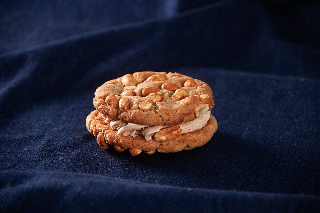 Chocolate chip cookies with almond slices on dark fabric background.