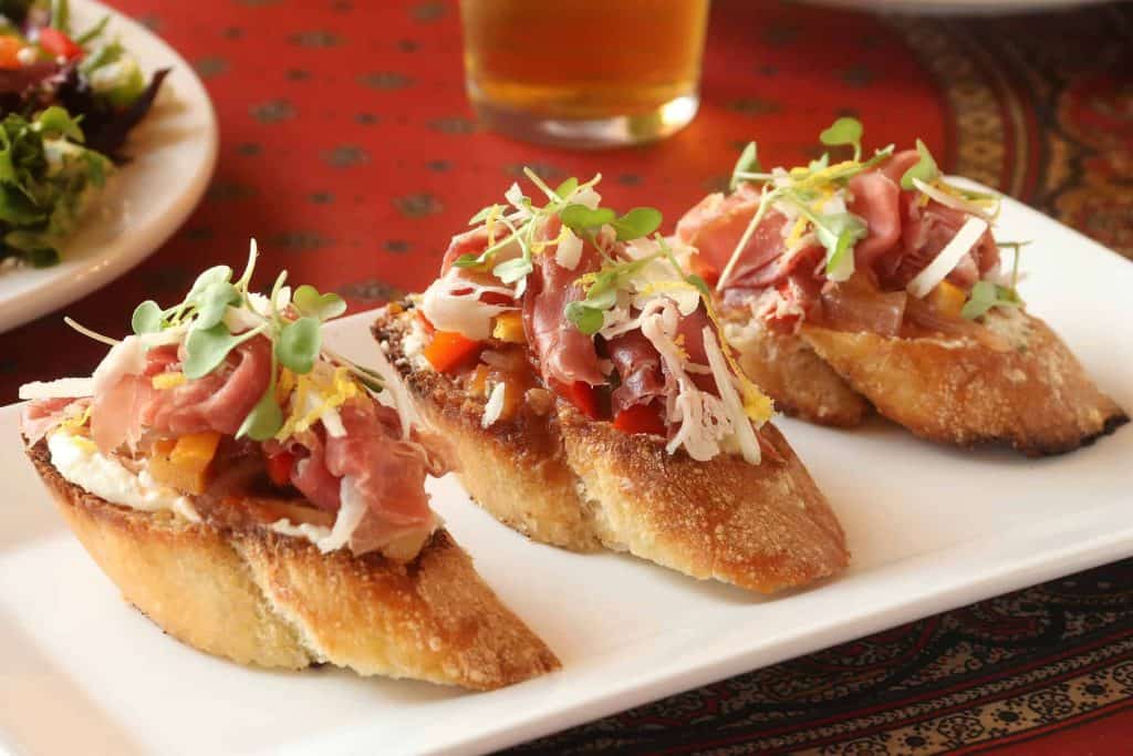 Delicious prosciutto crostini with microgreens on toasted baguette slices.