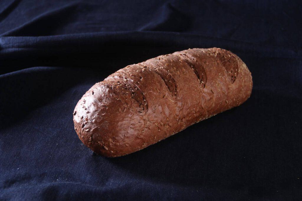 Freshly baked pumpernickel rye bread on dark fabric background.