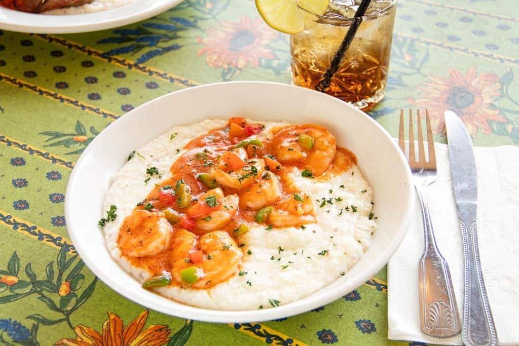 Shrimp and grits served with green onions on a white bowl.