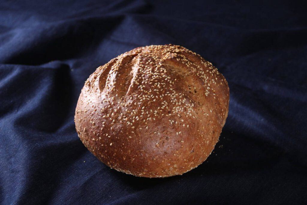 Freshly baked six grain sourdough bread on dark fabric background.