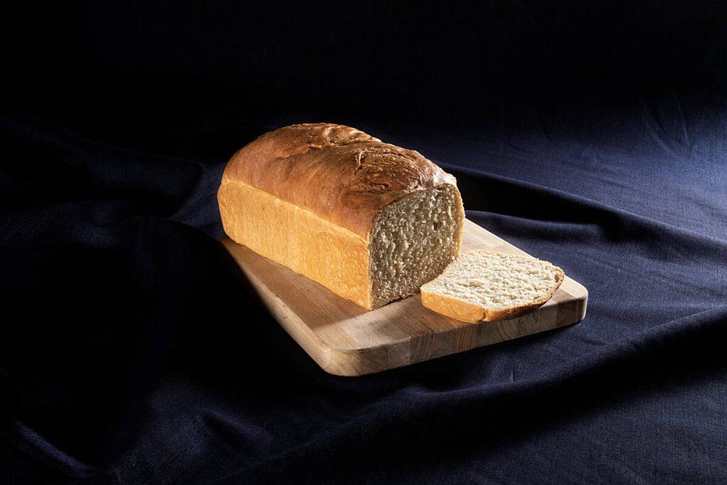 Freshly baked classic white bread loaf on a wooden board.
