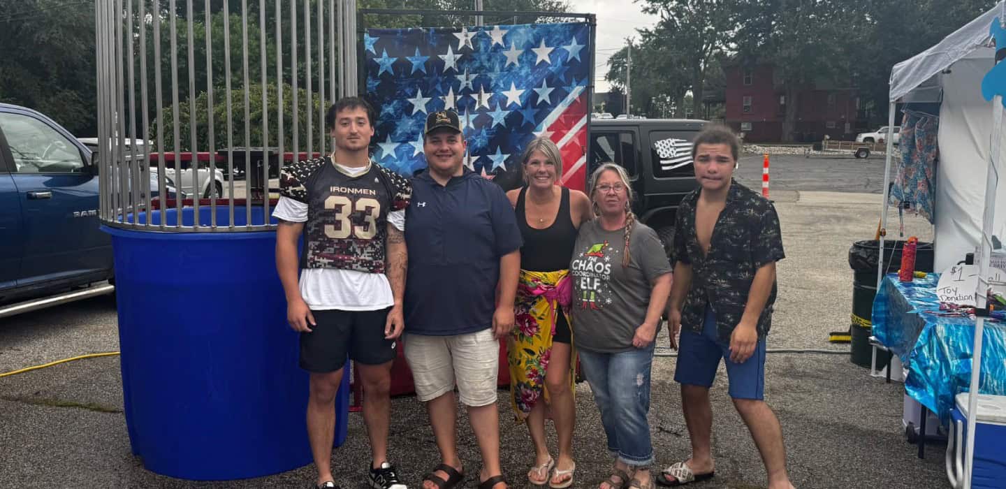 Group of fans at West Michigan Ironmen game with patriotic backdrop.