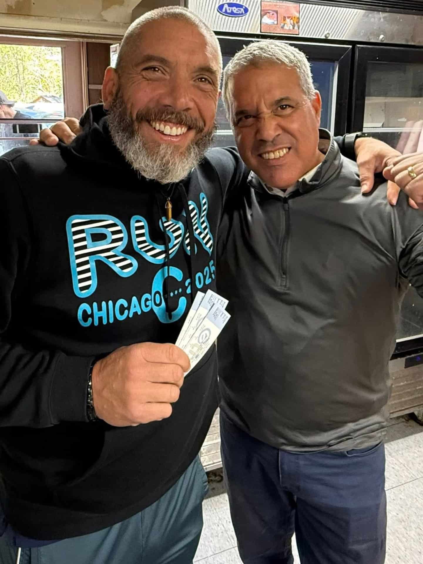 Two men celebrating, one holding a dollar bill, at West Michigan Ironmen game.