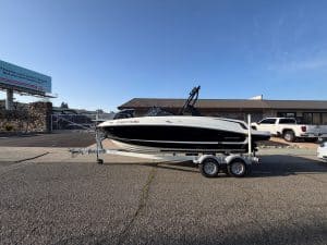 Bayliner VR5 boat on trailer at dealership lot with vehicles in background.