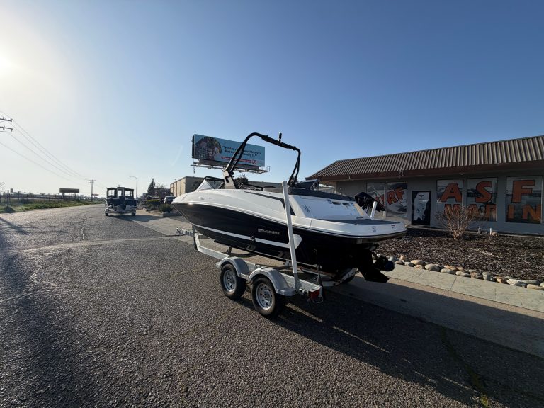 Bayliner VR5 boat on trailer outside dealership with clear sky.