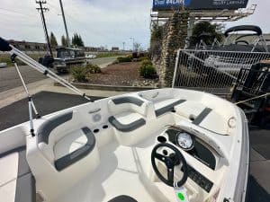Boat dashboard with steering wheel, gauges, and seating for passengers.