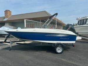Opti sailboat on trailer with outboard motor, ready for water adventures.