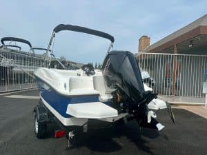 Boat with outboard motor on trailer at marina for sale or rent.