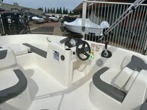 Boat cockpit with steering wheel and control panel at a marina.
