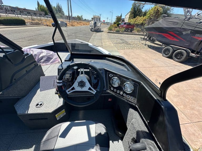 View of boat dashboard with steering wheel and gauges at marina.