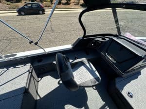 Close-up of boat's dashboard and steering console with windshield.