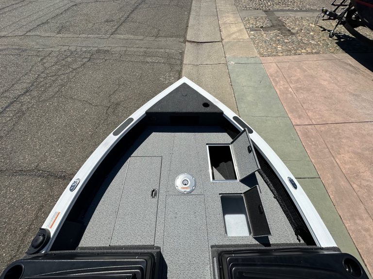 Close-up of boat deck with storage compartments and fishing accessories.