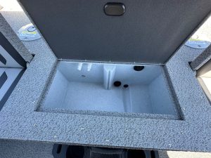 Boat storage compartment with carpeted interior and drainage holes.