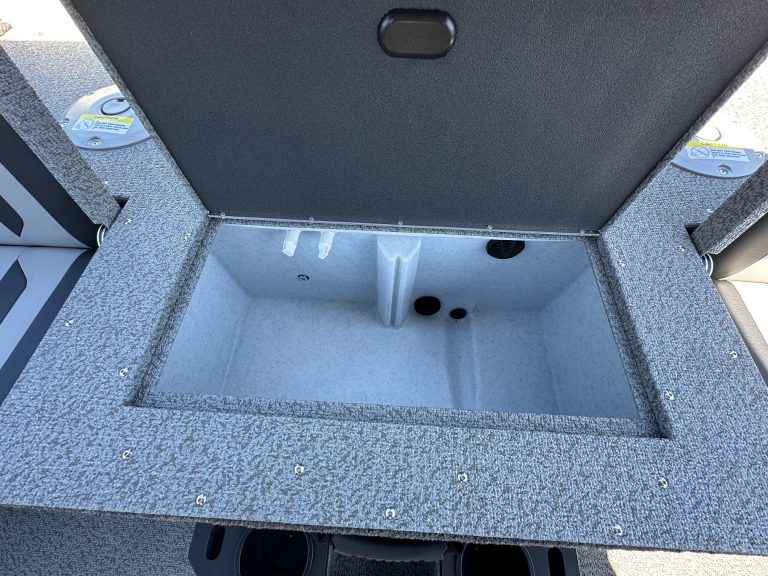 Boat storage compartment with carpeted interior and drainage holes.