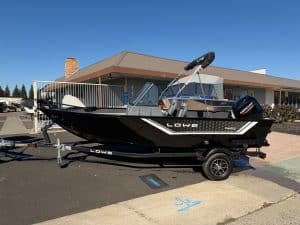 Lowe FM 1625 WT boat featuring Mercury 60HP outboard motor, parked on trailer outside a building.