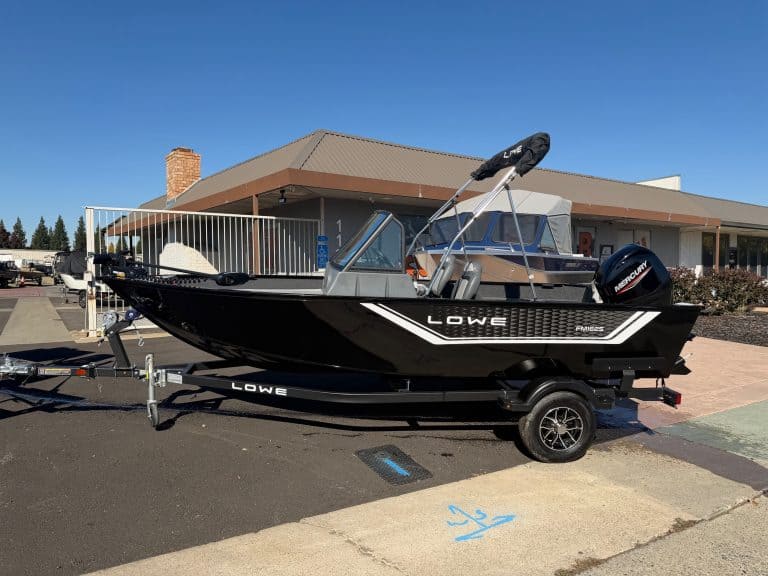 Lowe FM 1625 WT boat featuring Mercury 60HP outboard motor, parked on trailer outside a building.