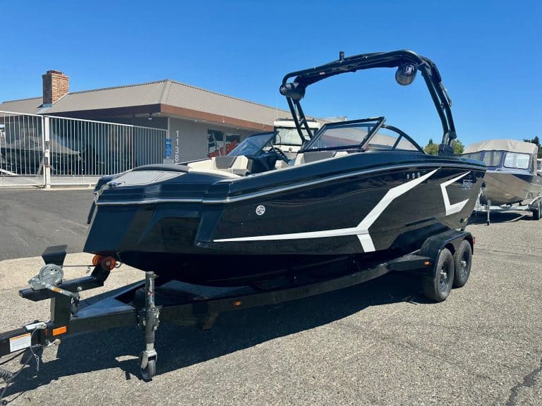 Black and white boat on trailer at marina for sale or rent.