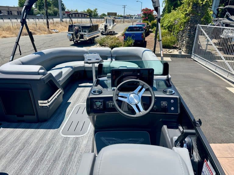 Modern pontoon boat cockpit with steering wheel and navigation system.