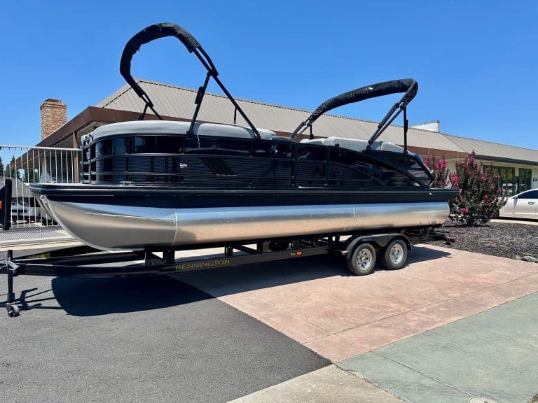 Modern black and silver pontoon boat on trailer at ASFB Marine dealership.