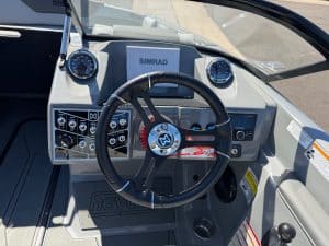 Boat dashboard with steering wheel, gauges, and electronics for surfing.