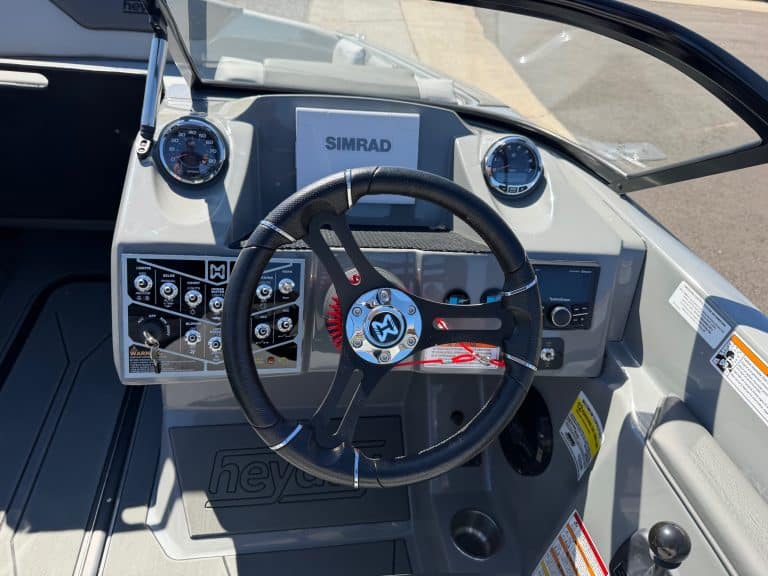 Boat dashboard with steering wheel, gauges, and electronics for surfing.