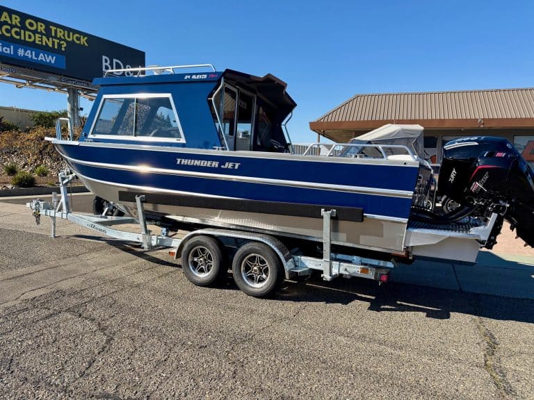 Boat on trailer with outboard motor, blue and white color scheme.