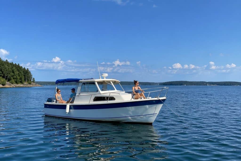 Boat on the water with two people enjoying a sunny day.