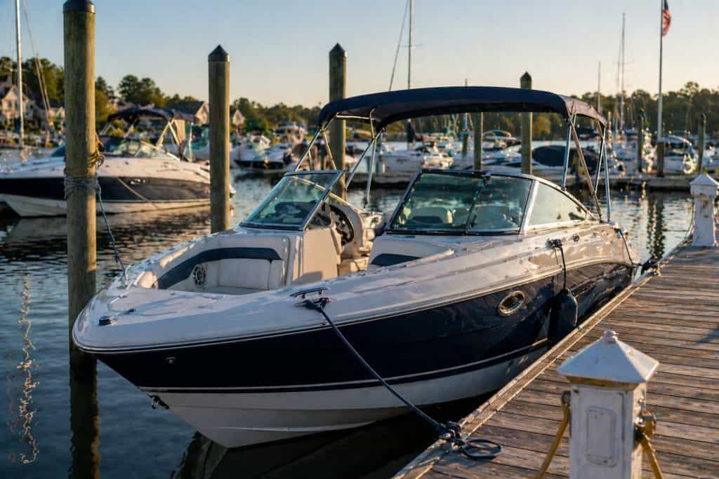 Luxury motorboat docked at marina with calm waters and other boats in background.