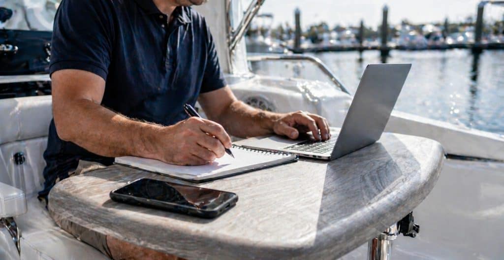 Man filling out a boat service appointment form on a marina dock.